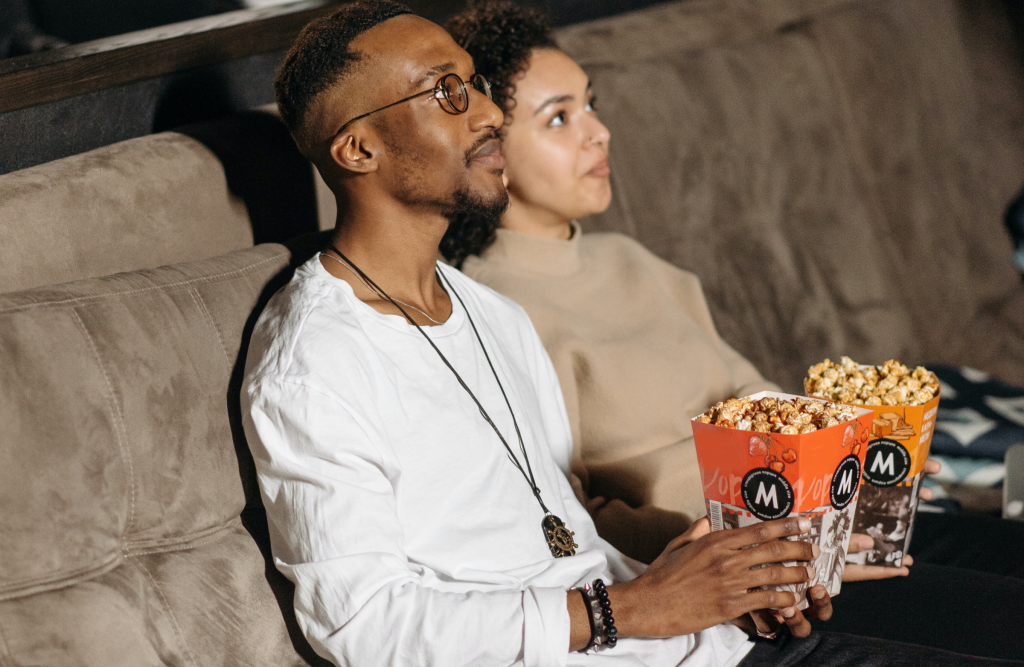 Man and woman in a movie theater with popcorn. 